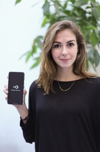 Stephanie Campbell wearing black top holding phone with OKKO Health app