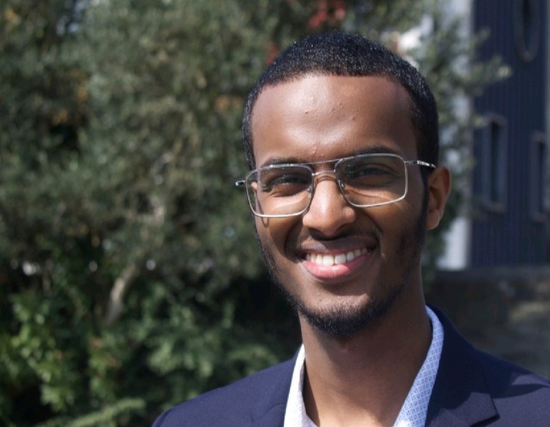 Omar Mahamed, founder of Dash, smiling, wearing a suit, standing in front of trees