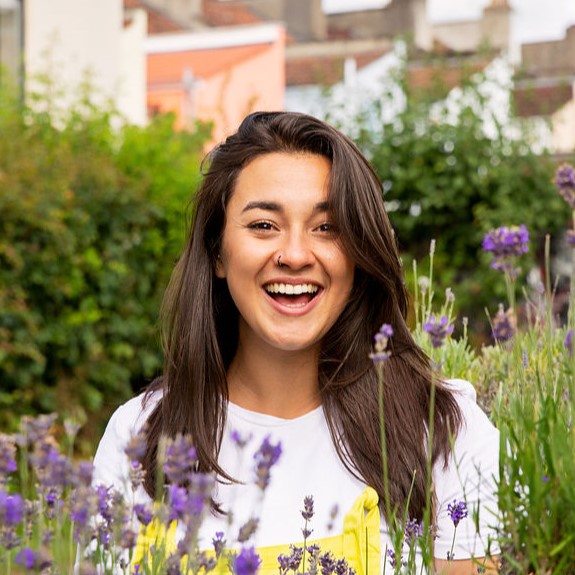 Devon Lowndes, Founder and Director of Self Agency, standing in a wild flower meadow, smiling