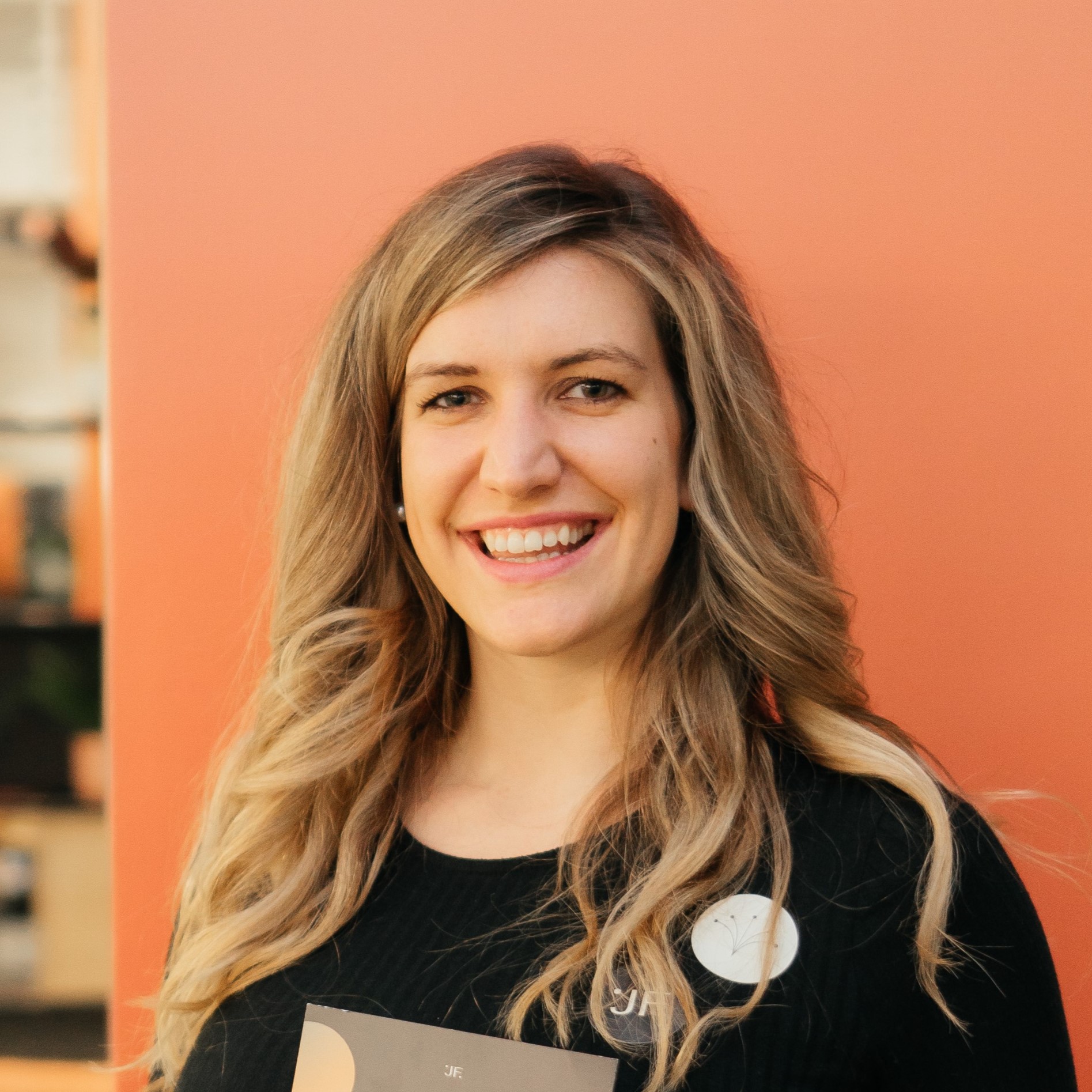 Lily Elsner, Founder of Jack Fertility, smiling wearing black top in front of orange background