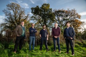 Wilder Sensing team of five people in a field with trees