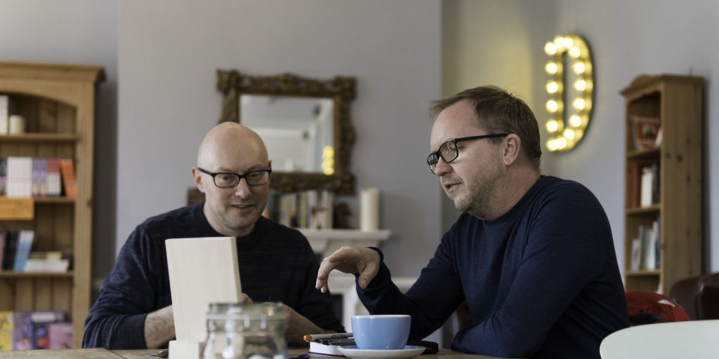 Two men at a table reading over documents