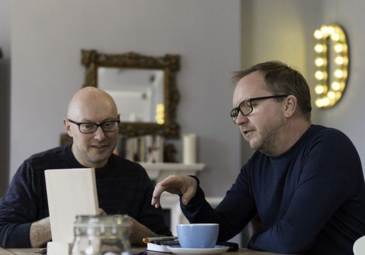 Two men at a table reading over documents