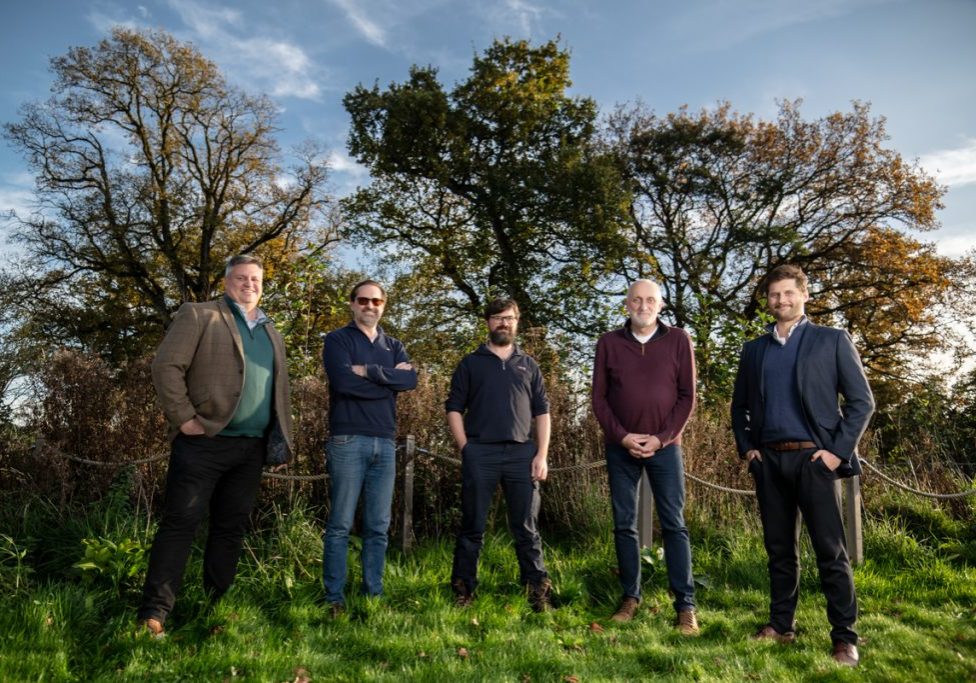 Wilder Sensing team of five people in a field with trees