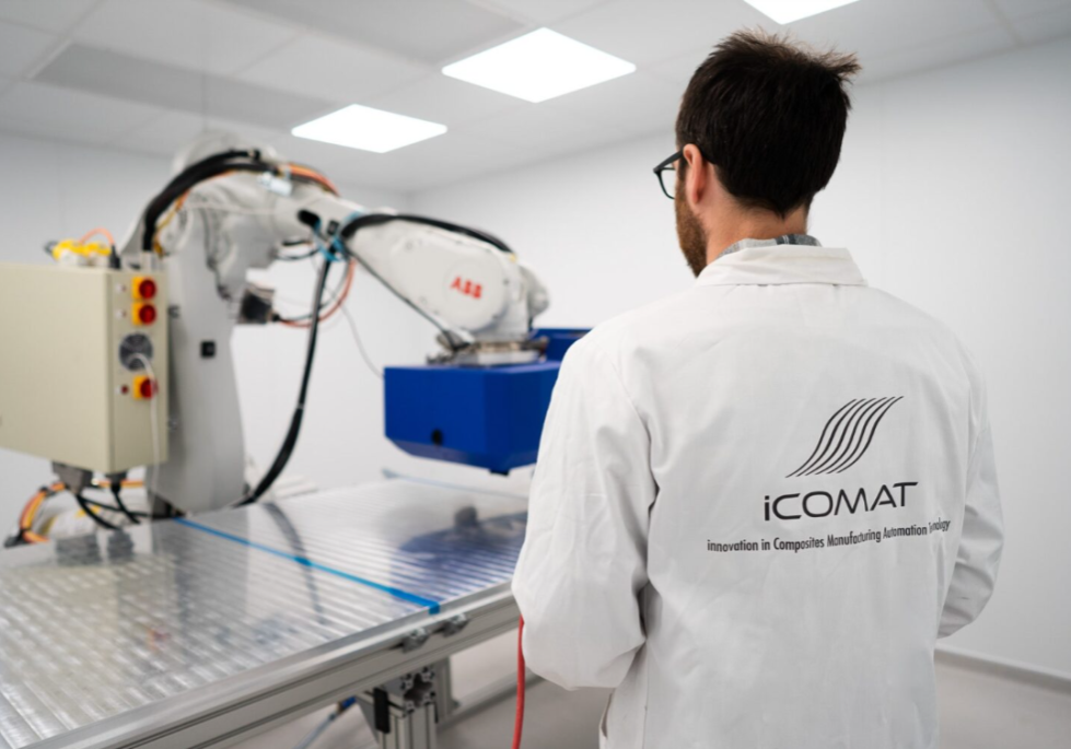 A scientist in the lab wearing white coat with iCOMAT logo, and engineering device